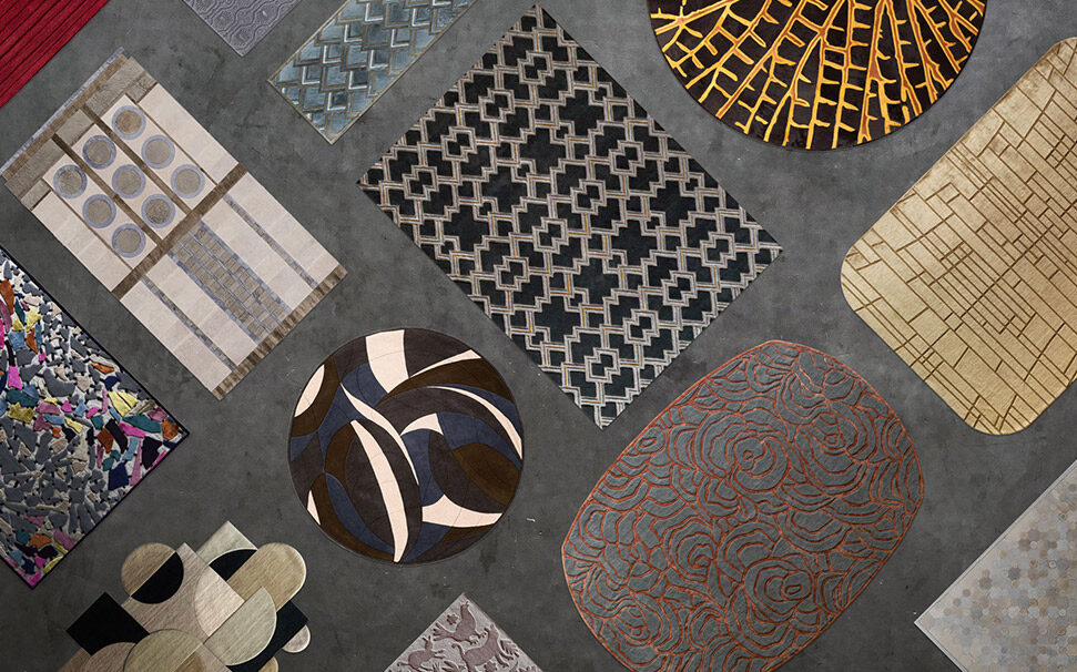 Luxury designer rugs in silk, hide, and wool with abstract patterns on concrete.