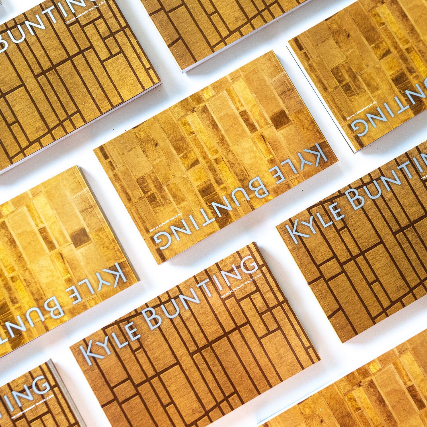 Rectangular "KYLE BUNTING" books in gold pattern on white, diagonal grid.