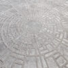 Luxury custom round designer rug with maze pattern on smooth gray floor.