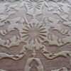 Luxury custom designer rug in beige and tan with raised animal and sunburst motifs.