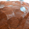 Close-up of a luxury custom designer rug with textured brown shapes on gray floor.