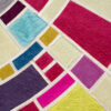 Luxury designer rug with geometric patchwork in silk, wool, and hide textures.