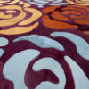 Close-up of luxury designer rug Procession 24968, handmade wool and silk, with swirling blue, yellow, orange, and burgundy patterns.