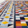Close-up of Lady 24390, a vibrant luxury designer wool rug with geometric pattern.