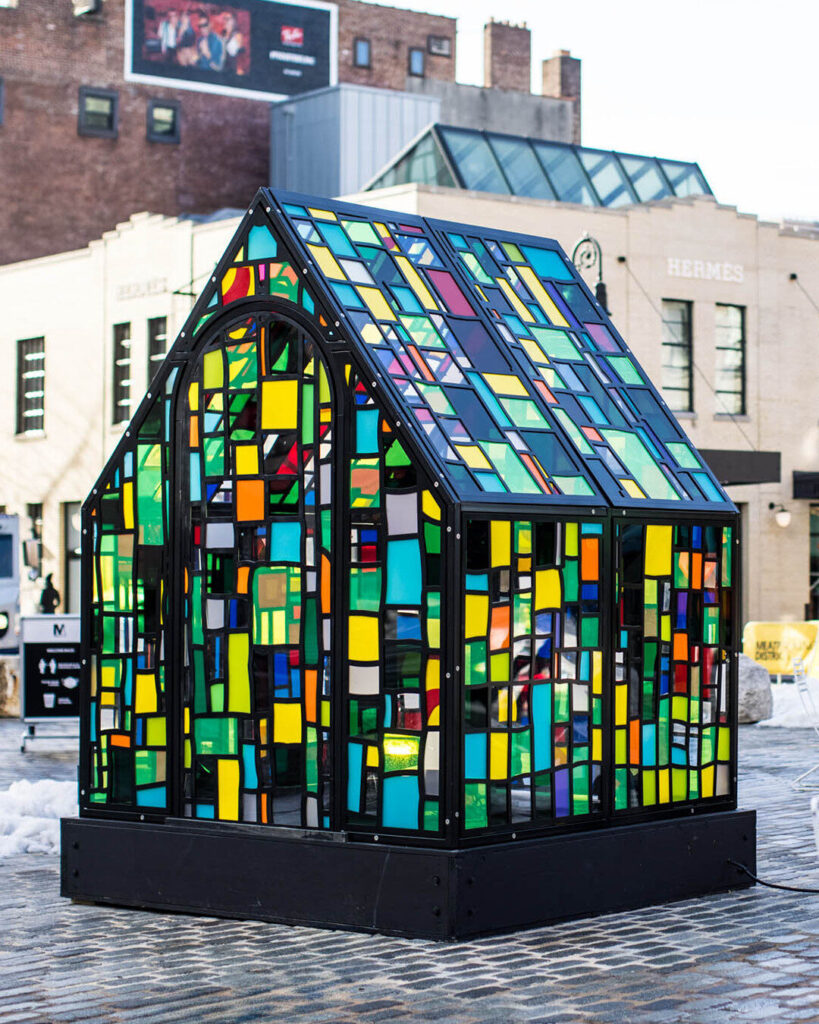 A stained glass greenhouse in a plaza is accented by luxury designer rugs.