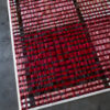 Close-up of a luxury designer custom wool rug with red check pattern on concrete floor.