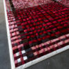 Luxury custom designer rug in red, pink, and black plaid on a gray floor.