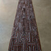 Luxury designer rectangular rug with geometric pattern in brown and gray on concrete.