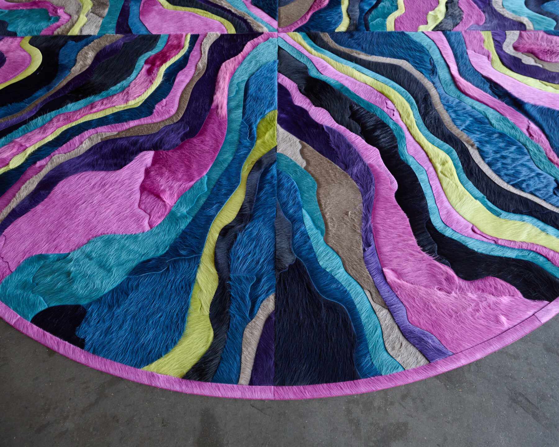 A close-up of the Submerge 12987 luxury designer rug with wavy, multicolored patterns on a gray floor.
