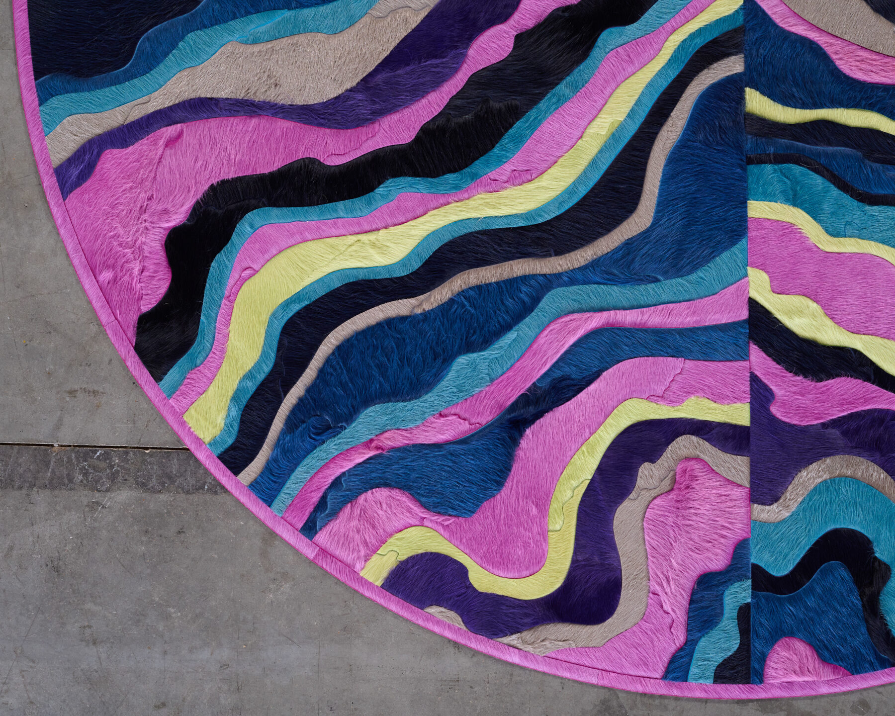 A close-up of the Submerge 02842 luxury designer rug with wavy multicolor stripes melting into a concrete floor.