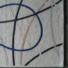Luxury designer rug with a textured beige base, intersecting lines, and a blue oval accent.