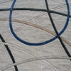 Luxury designer rug with abstract curves in gray, black, beige, and a bold blue oval.