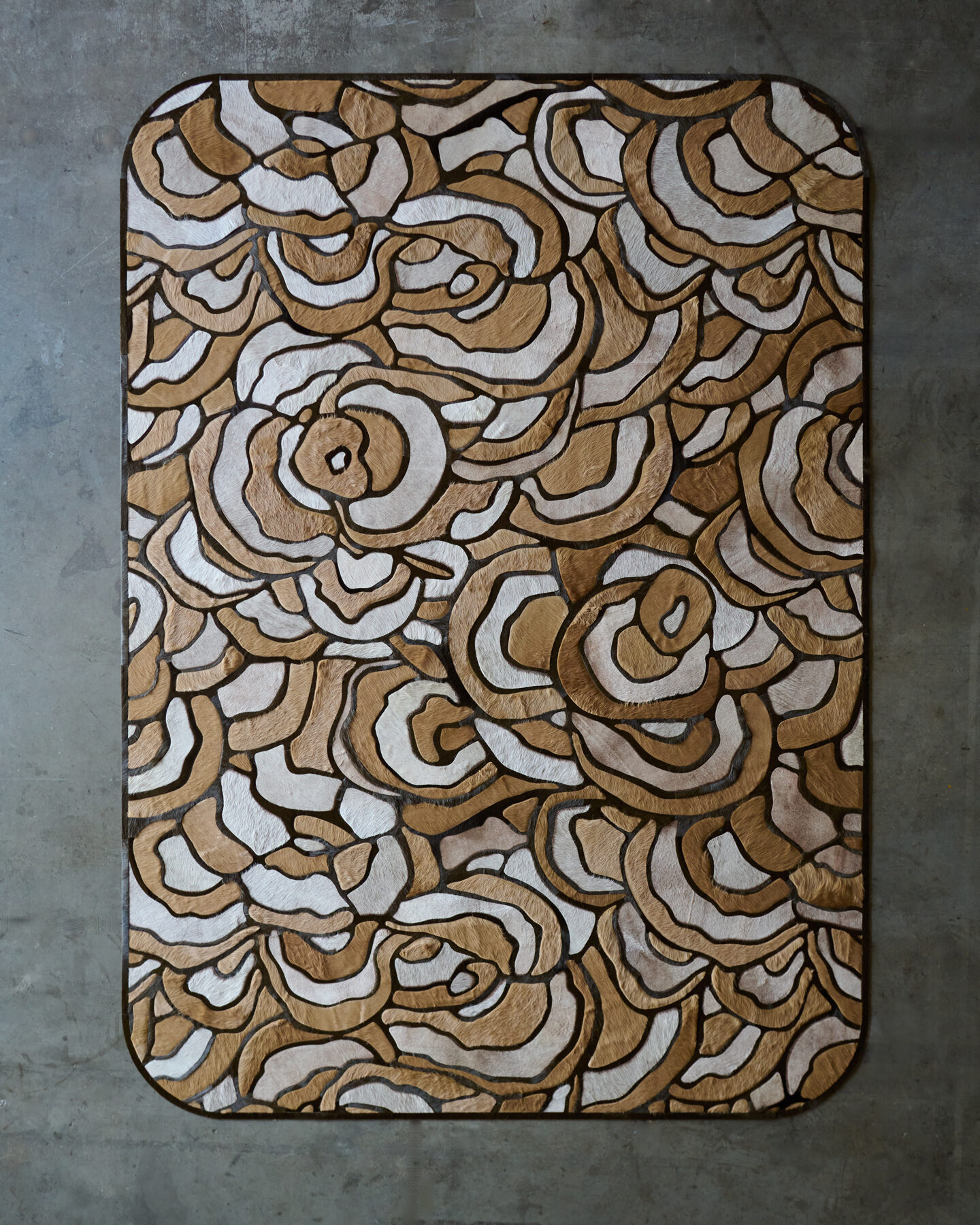 The Bloom 02710 luxury designer rug features a high-end abstract beige and brown pattern on concrete.