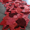 Luxury designer rug Custom 02811 with red and pink organic shapes on a concrete floor.