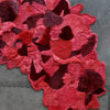 Luxury custom designer rug 02811, irregular red and pink wool, petal motif on concrete.