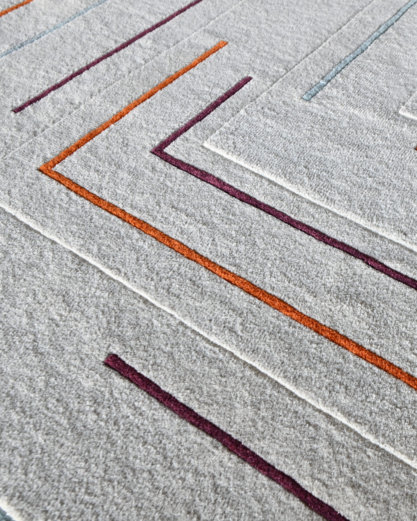 Close-up of Faceta 2321 high end designer rug with textured gray base and colorful angular lines.
