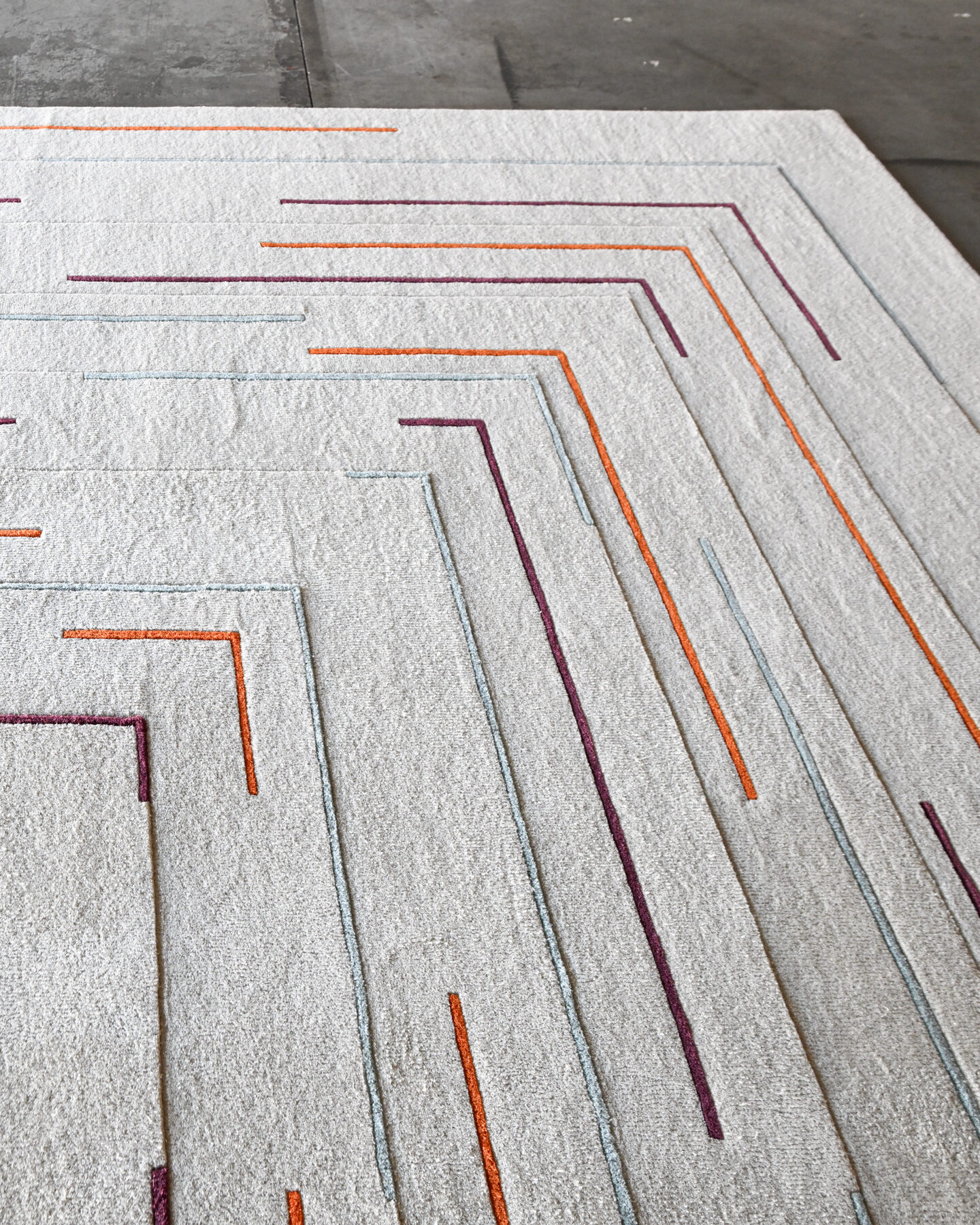 The Faceta 2321 is a luxury designer rug, hand-tufted with multicolored geometric lines on a light background.