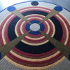 Atlas 03269 luxury designer rug with concentric rings and blue accents on a gray floor.