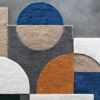Luxury designer rug with a geometric blue, beige, gray, white, and orange pattern on concrete.
