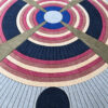 This luxury designer rug features concentric circles in blue, red, beige, and gray with intersecting lines and bold black dots.