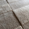 Close-up of a high-end luxury custom rug with a textured grid, resembling stone tiles.