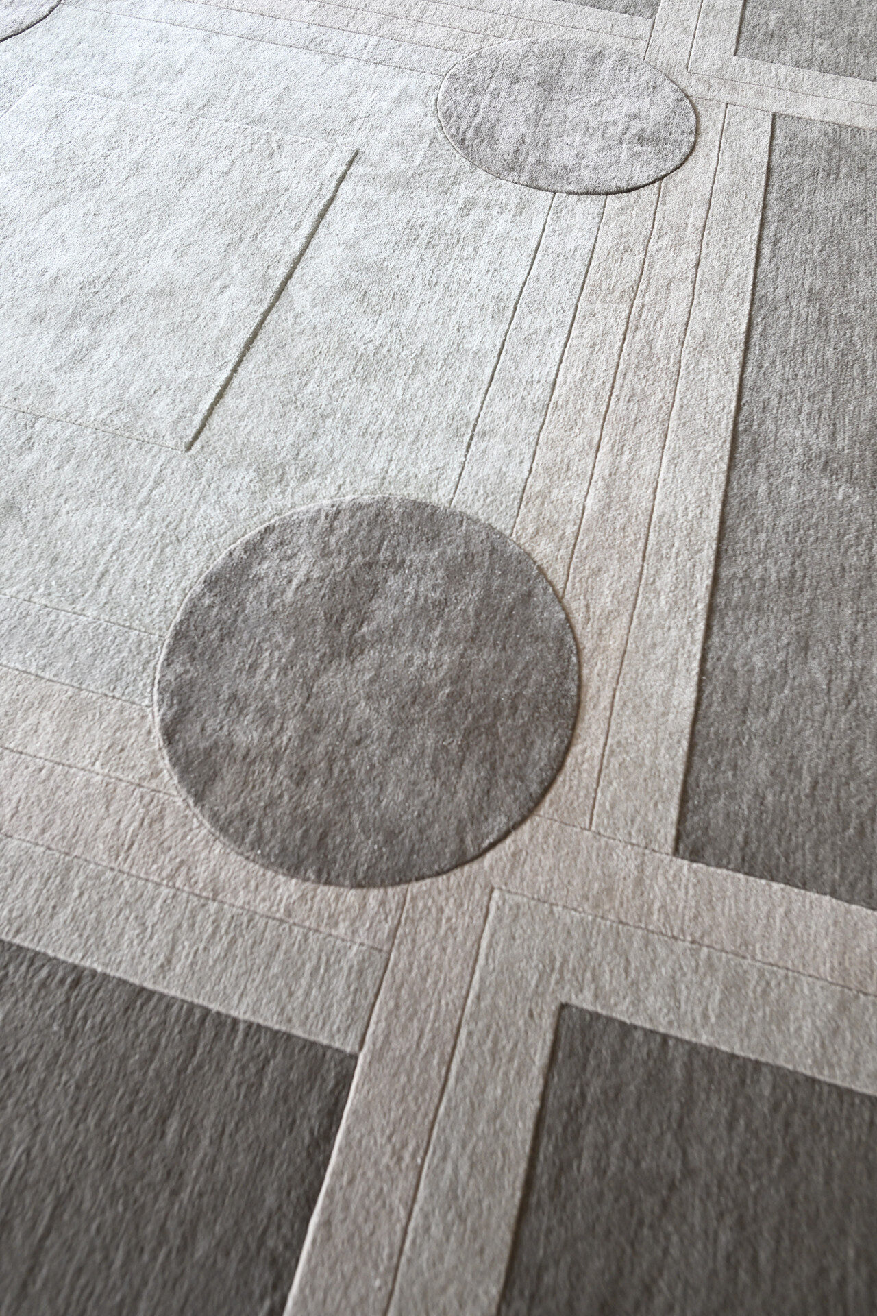 Close-up of Atlas 03141 luxury designer rug with intersecting lines and circles in soft gray tones.