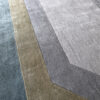 A close-up of the Atlas 03141 designer rug featuring luxury geometric patterns in gray, taupe, and olive green.