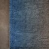 Close-up of Custom 03236 luxury designer rug, blue-gray high-end wool on brown floor.