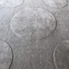 A close-up of Atlas 03145, a luxury designer rug with geometric circles on gray wool.