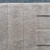 Luxury designer rug in beige with geometric raised patterns, high-end custom wool design on concrete floor.