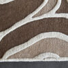 Close-up of Bloom 03448 designer rug, a high end textured beige and brown luxury wool rug on a smooth gray floor.