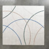 Luxury designer rug with beige base and intersecting blue, brown, black, and gray lines on a smooth gray floor.