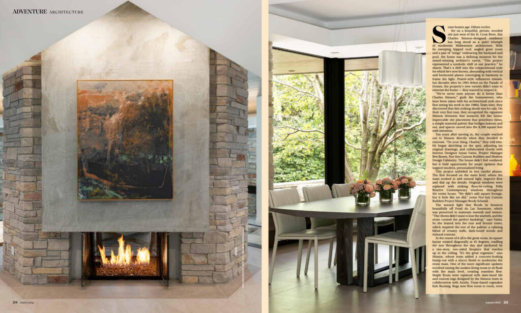 A stone fireplace and painting beside a modern dining area with designer rugs and large windows.