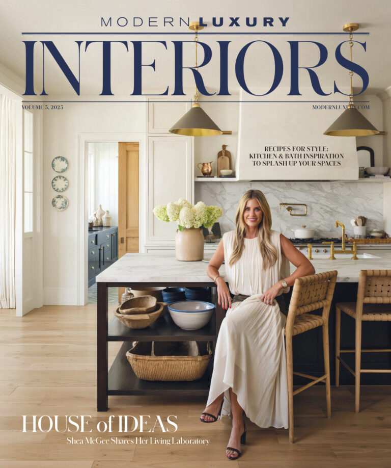 A woman in a white dress sits on a kitchen island stool above a luxury custom designer rug in a bright, modern kitchen.