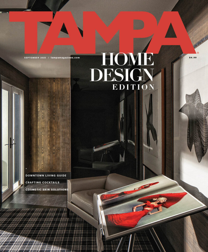 A modern living room features a high end custom rug, neutral armchair, and framed art.
