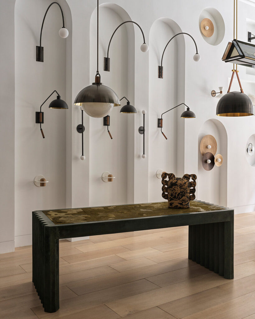 A modern interior with a high end dark green bench atop a luxury designer wool rug, framed by sculptural decor and contemporary lighting.