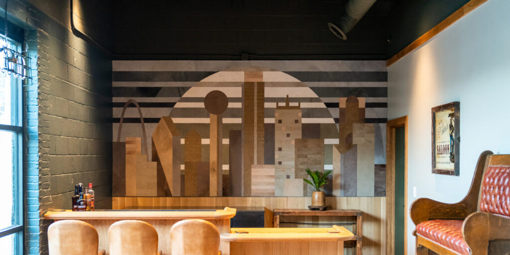 A modern bar with a designer luxury custom rug beneath tan leather stools and a wood counter.