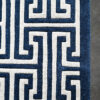 Close-up of the Ripcord 03227 luxury designer rug in blue and white Greek key pattern on gray floor.