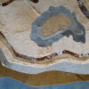 Aerial view of a luxury custom designer rug with abstract beige, brown, and gray shapes on a blue-gray floor.