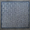 Luxury designer area rug with Greek key pattern in navy and white on a gray floor.