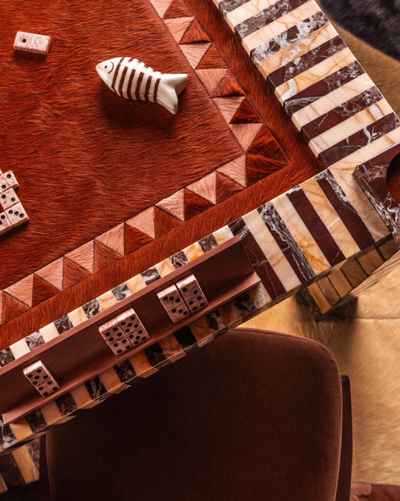 A close-up of a designer game table on a luxury custom rug, showing geometric patterns and dominoes.