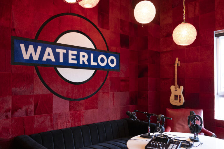 A recording studio with red walls and a high end designer rug beneath the round table.