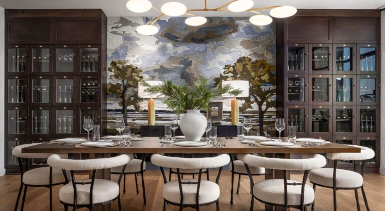 A modern dining room features a designer rug under a long table and eight chairs.