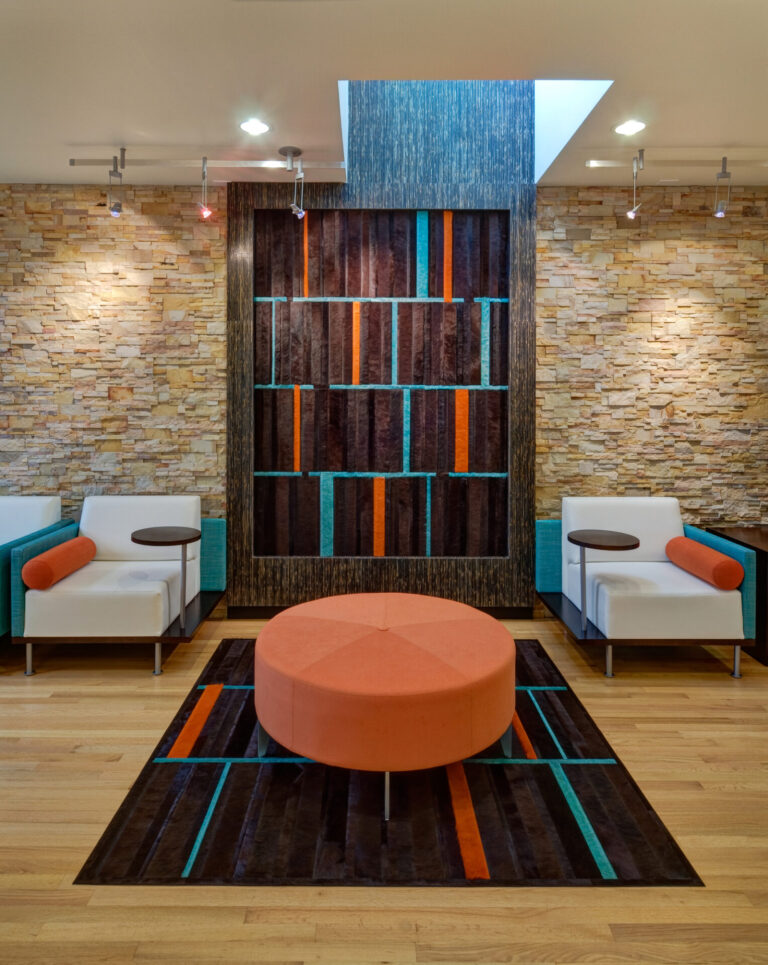 A room with designer chairs showcases a luxury custom round orange and blue high-end rug.