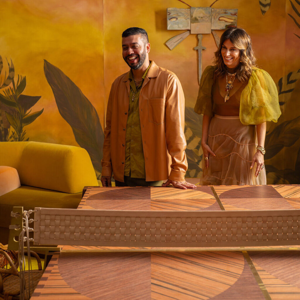 Two people stand by a table on luxury designer rugs, with high-end rug decor and warm tones.