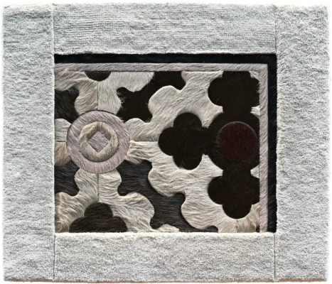 A luxury designer rug with a textured cream border and abstract black, brown, and white motifs.
