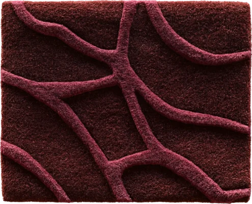 A close-up of a luxury designer rug featuring dark red textured waves in an irregular high-end pattern.