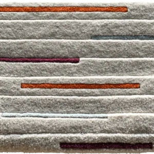 Luxury designer area rug with textured gray base, subtle stripes, and bold accent colors.
