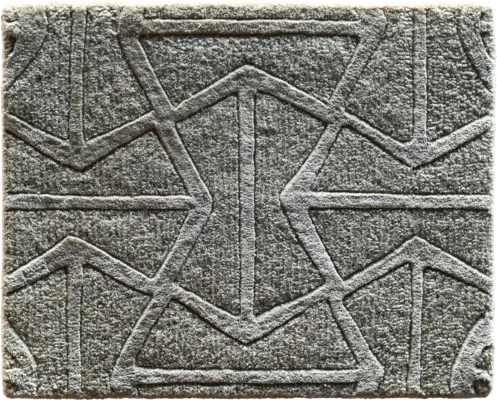 A close-up of a luxury designer gray rug features textured, geometric raised patterns in high-end, custom quality.