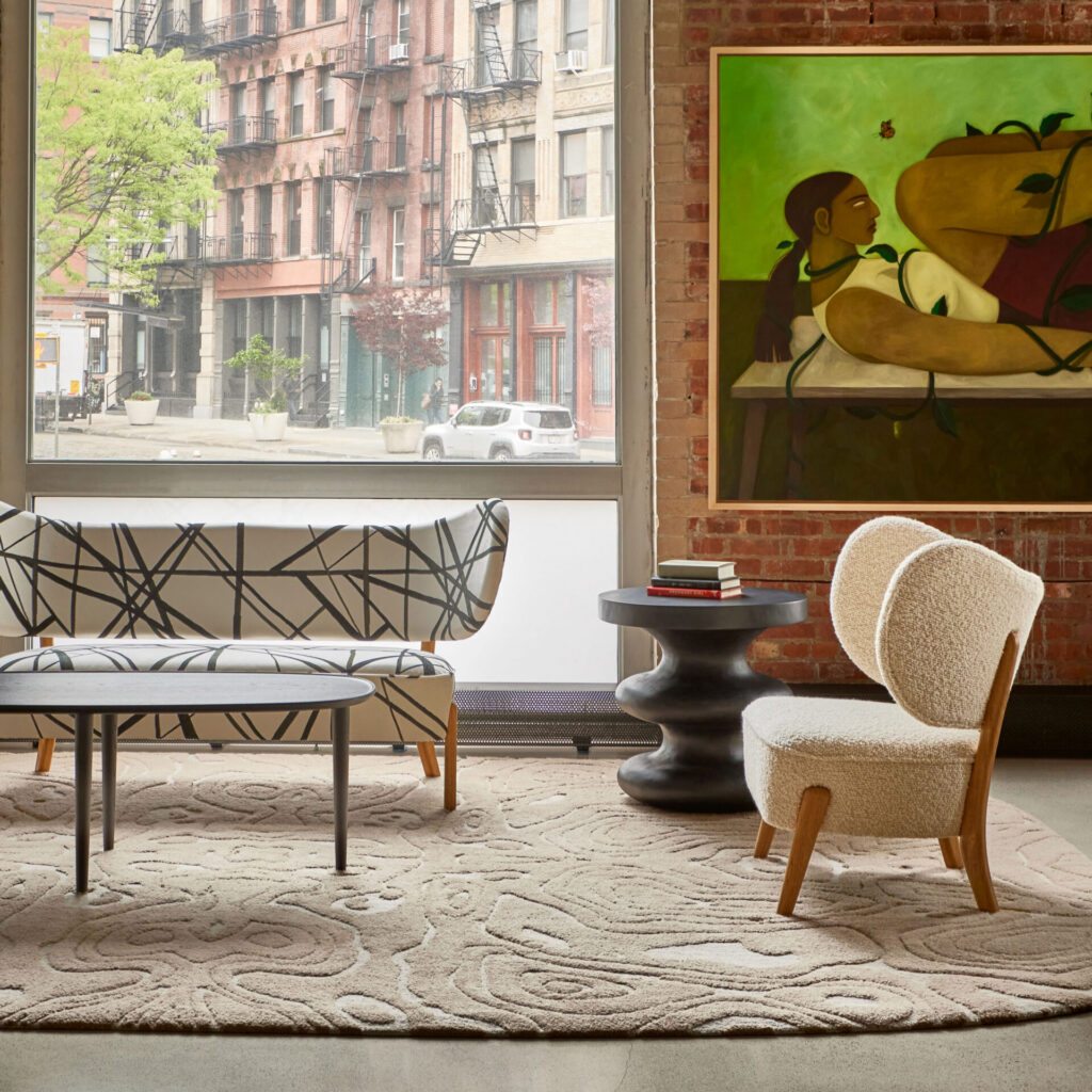 A modern living room with a high end designer rug, patterned sofa, and large windows.